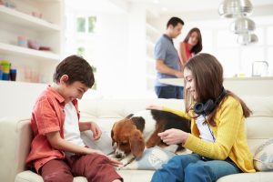 two-kids-and-a-dog-playing-indoors-with-parents-in-the-background